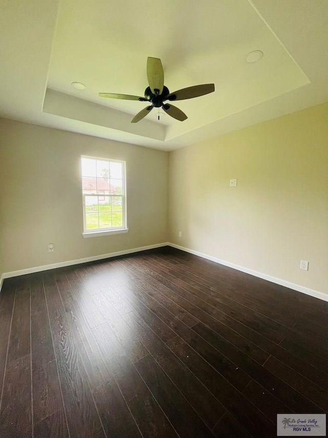 unfurnished room featuring dark hardwood / wood-style floors, a raised ceiling, and ceiling fan