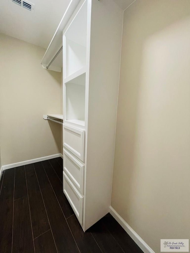 walk in closet with dark hardwood / wood-style flooring