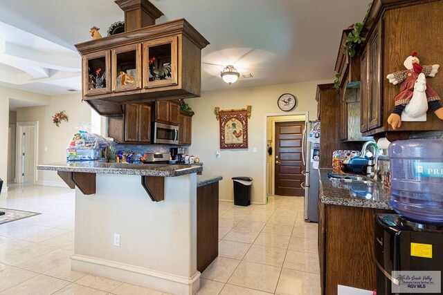 kitchen with a kitchen bar, appliances with stainless steel finishes, backsplash, sink, and light tile patterned floors