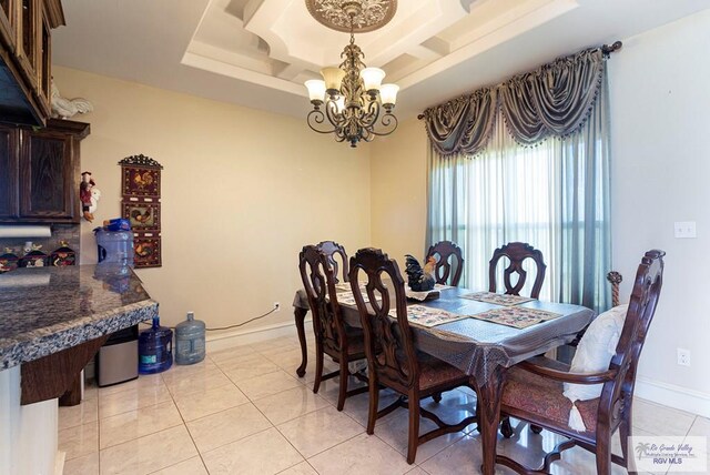 dining space featuring a tray ceiling, a notable chandelier, and light tile patterned flooring