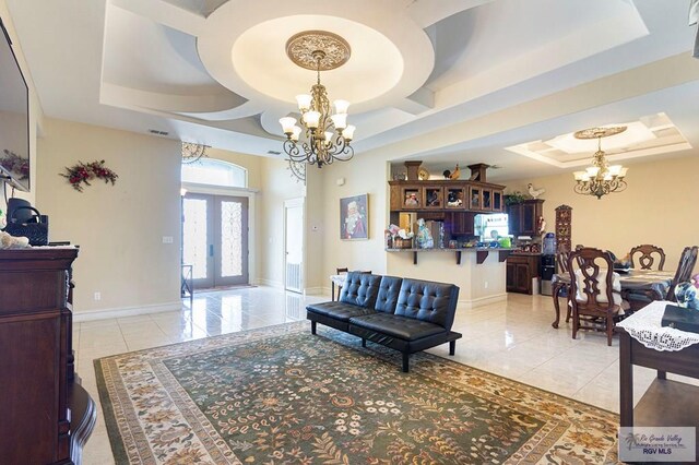 tiled living room featuring a notable chandelier, french doors, and a tray ceiling