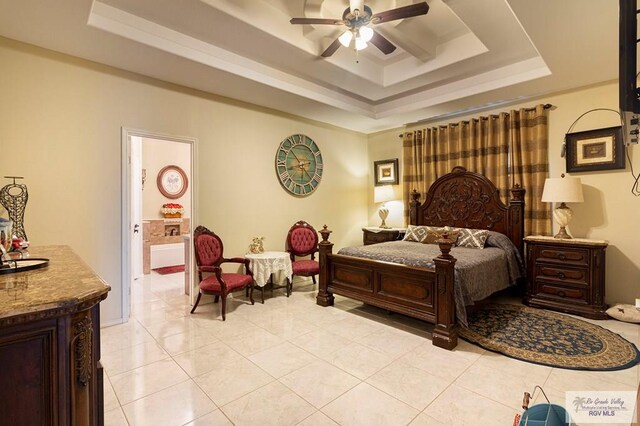 bedroom with ceiling fan, a raised ceiling, light tile patterned floors, and ensuite bath