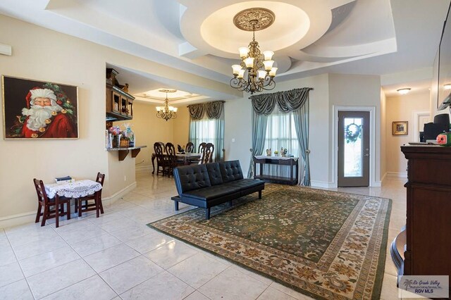 tiled living room with a raised ceiling and an inviting chandelier