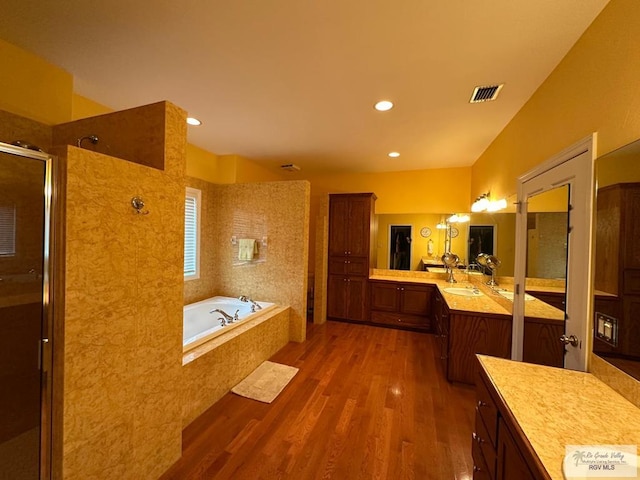 full bath featuring a garden tub, wood finished floors, vanity, visible vents, and a tile shower