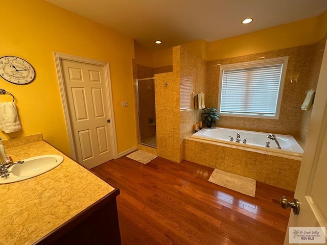 bathroom featuring a garden tub, recessed lighting, wood finished floors, vanity, and a shower stall