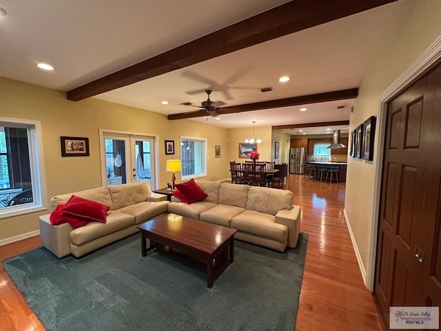 living room with baseboards, wood finished floors, beam ceiling, and a healthy amount of sunlight