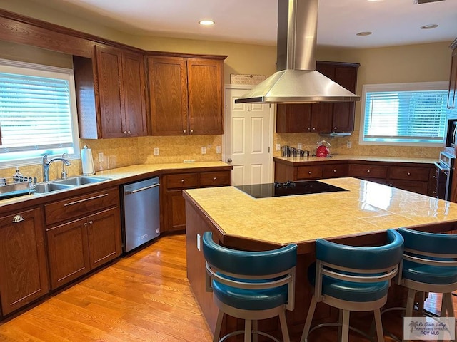 kitchen featuring stainless steel appliances, light countertops, a kitchen island, and island range hood