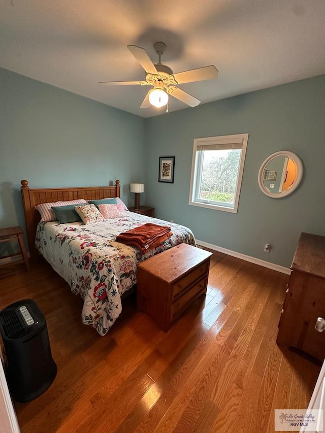 bedroom featuring wood finished floors, a ceiling fan, and baseboards