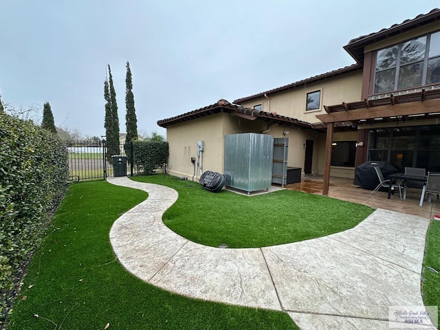 rear view of house featuring a yard, a patio, fence, and stucco siding