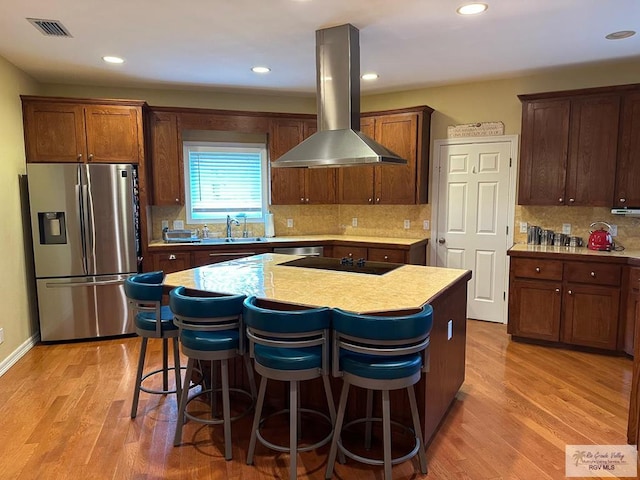 kitchen with a kitchen island, island range hood, black electric cooktop, and stainless steel fridge with ice dispenser