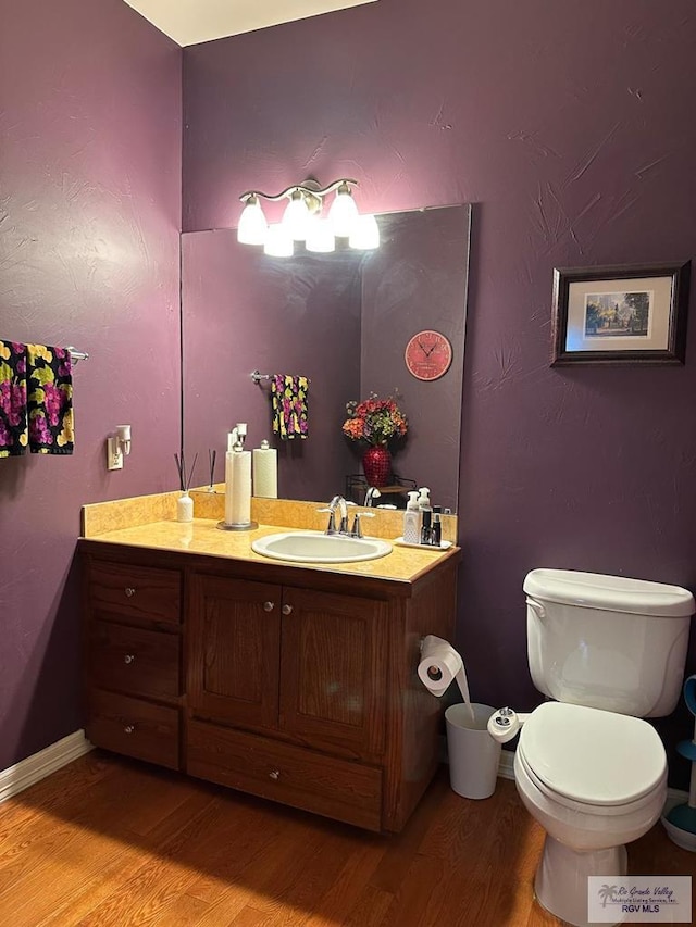 bathroom featuring baseboards, vanity, toilet, and wood finished floors