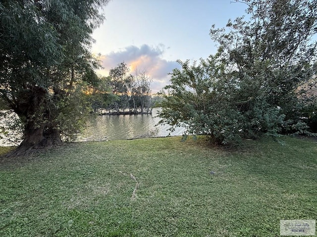 yard at dusk featuring a water view