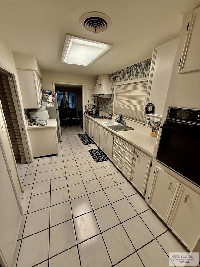 kitchen featuring light tile patterned flooring, stainless steel refrigerator, sink, oven, and custom exhaust hood