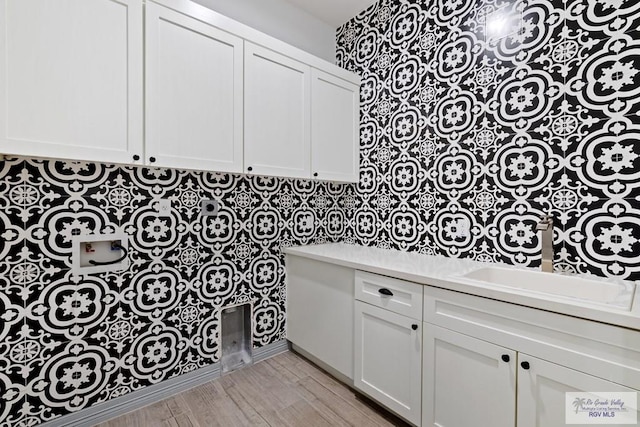 clothes washing area with cabinets, hookup for a washing machine, and light hardwood / wood-style flooring