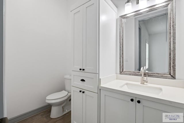 bathroom with vanity, toilet, and hardwood / wood-style floors