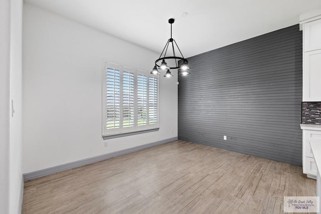 unfurnished dining area with light hardwood / wood-style floors and a notable chandelier