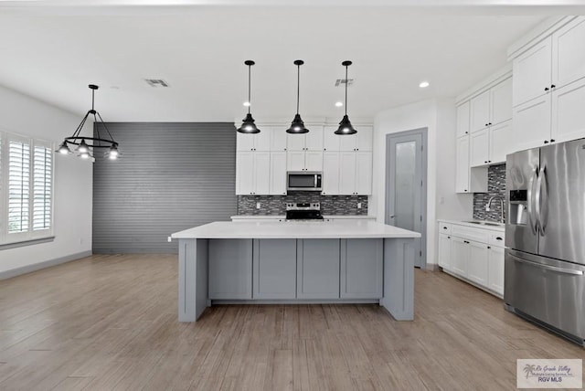 kitchen with hanging light fixtures, appliances with stainless steel finishes, a large island, and white cabinets