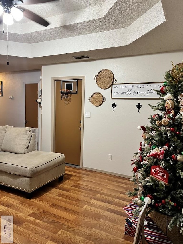 living area with hardwood / wood-style floors, a textured ceiling, and ceiling fan