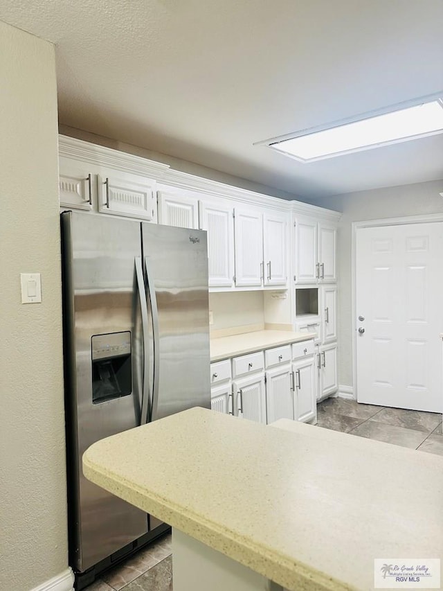 2200 E 19th St, Mission, TX 78572 - kitchen featuring stainless steel fridge with ice dispenser, white cabinetry, baseboards, and light tile patterned floors