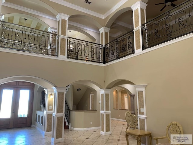 entrance foyer with ornate columns, french doors, a high ceiling, crown molding, and light tile patterned floors