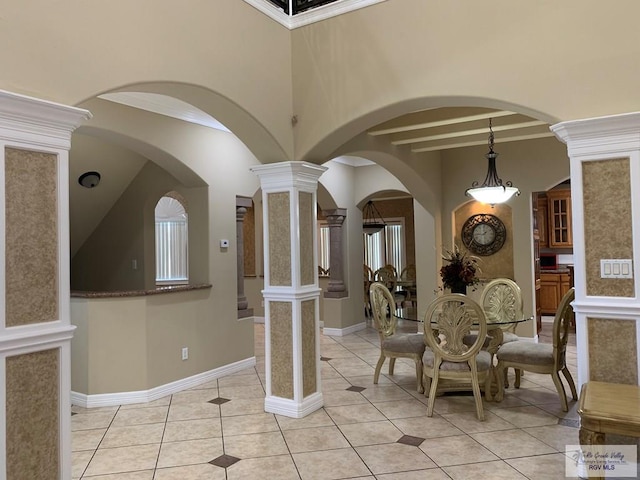 dining room featuring decorative columns, light tile patterned flooring, and ornamental molding