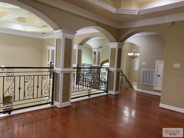 corridor featuring a raised ceiling, a chandelier, ornamental molding, and hardwood / wood-style flooring