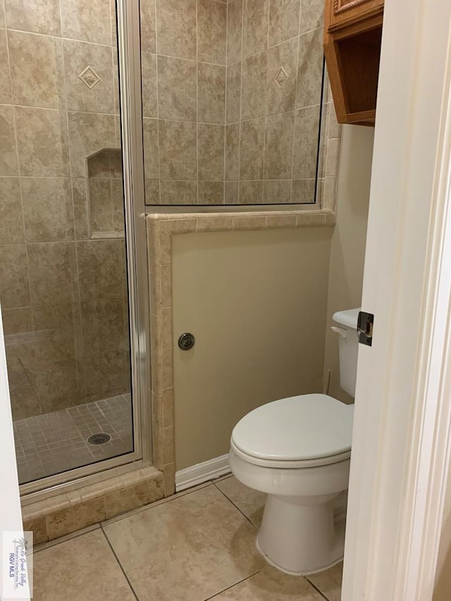 bathroom featuring tile patterned floors, toilet, and an enclosed shower