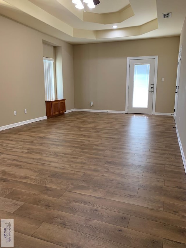 spare room with a tray ceiling, ceiling fan, and dark hardwood / wood-style flooring