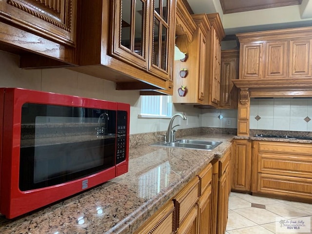 kitchen featuring sink, black gas cooktop, light stone counters, backsplash, and light tile patterned floors