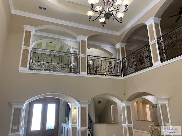 foyer with ornamental molding, a high ceiling, and ornate columns