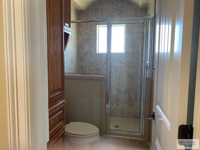 bathroom with tile patterned flooring, toilet, and a shower with shower door