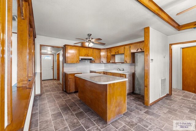 kitchen with backsplash, a kitchen island, ceiling fan, and sink