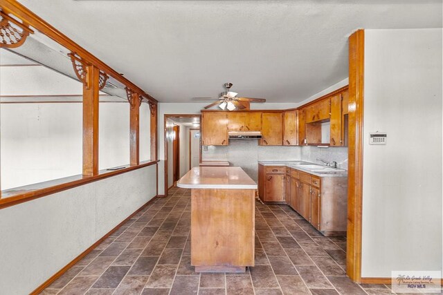 kitchen with backsplash, ceiling fan, a center island, and sink