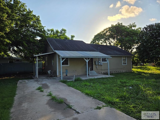 view of front facade featuring metal roof, driveway, and a front lawn