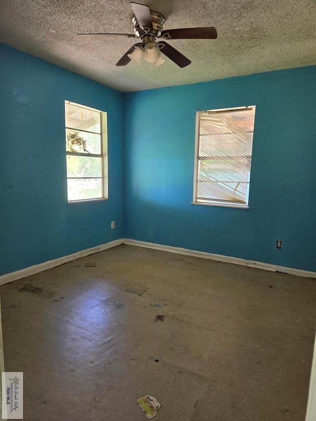 empty room featuring a ceiling fan, concrete floors, baseboards, and a textured ceiling