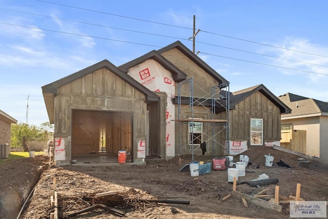 property in mid-construction with a garage, dirt driveway, central AC unit, and board and batten siding