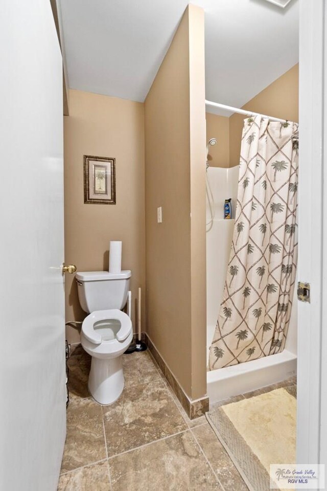 413 Cooper Ln Unit 24, 25, 26, La Feria, TX 78559 - bathroom with toilet, a shower stall, baseboards, and stone finish flooring