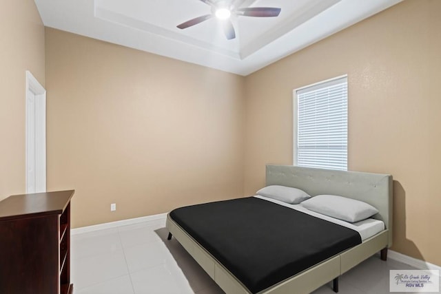 tiled bedroom featuring ceiling fan and a tray ceiling