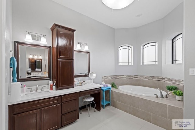 bathroom with a relaxing tiled tub, vanity, and tile patterned floors