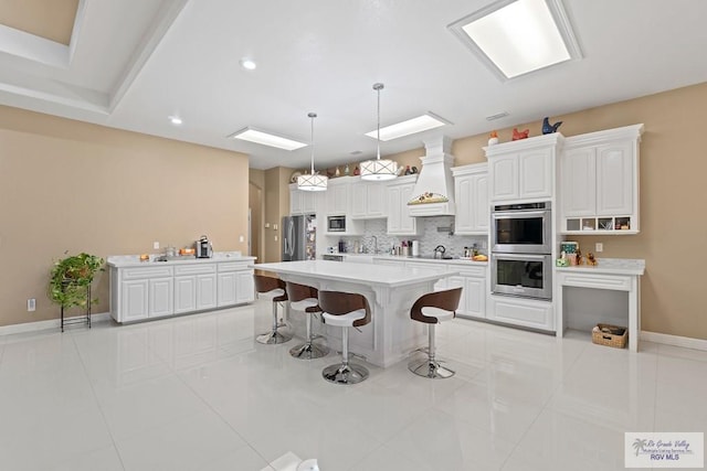 kitchen with custom exhaust hood, tasteful backsplash, a center island, pendant lighting, and white cabinets