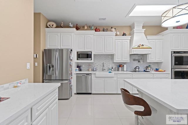 kitchen featuring appliances with stainless steel finishes, decorative light fixtures, sink, and white cabinets