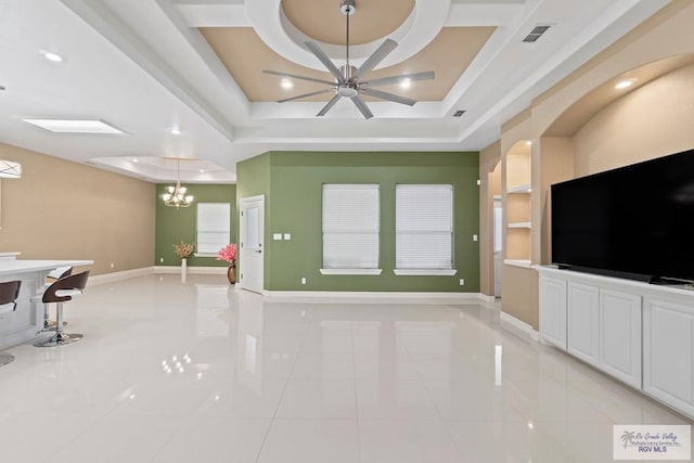 unfurnished living room with a raised ceiling, light tile patterned flooring, and ceiling fan with notable chandelier