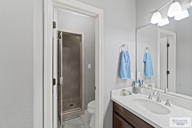 bathroom featuring vanity, a shower with shower door, tile patterned floors, and toilet