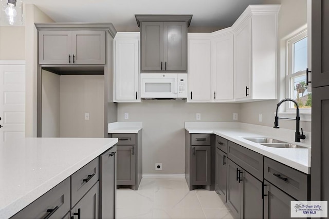 kitchen with white cabinets, gray cabinets, and sink