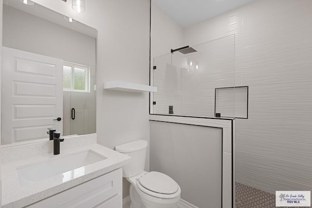 bathroom featuring vanity, a shower with shower door, and toilet