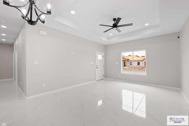 spare room with a raised ceiling and ceiling fan with notable chandelier