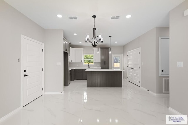 kitchen with a chandelier, a center island, decorative light fixtures, and stainless steel refrigerator