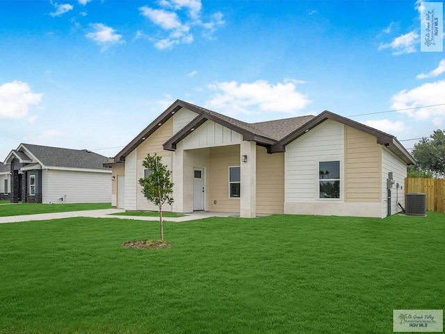 view of front of home featuring a front yard, a garage, and cooling unit