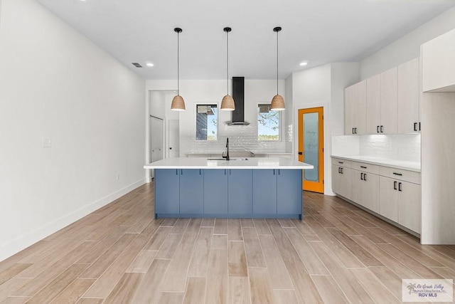 1421 6th St, Harlingen, TX 78550 - kitchen with wall chimney range hood, light countertops, light wood-style floors, tasteful backsplash, and recessed lighting