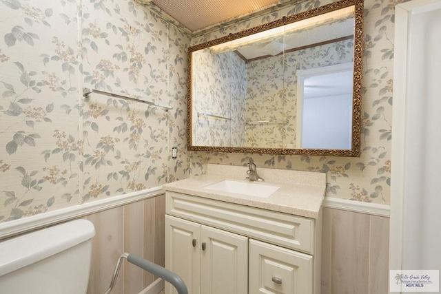 bathroom with vanity, wood walls, and toilet